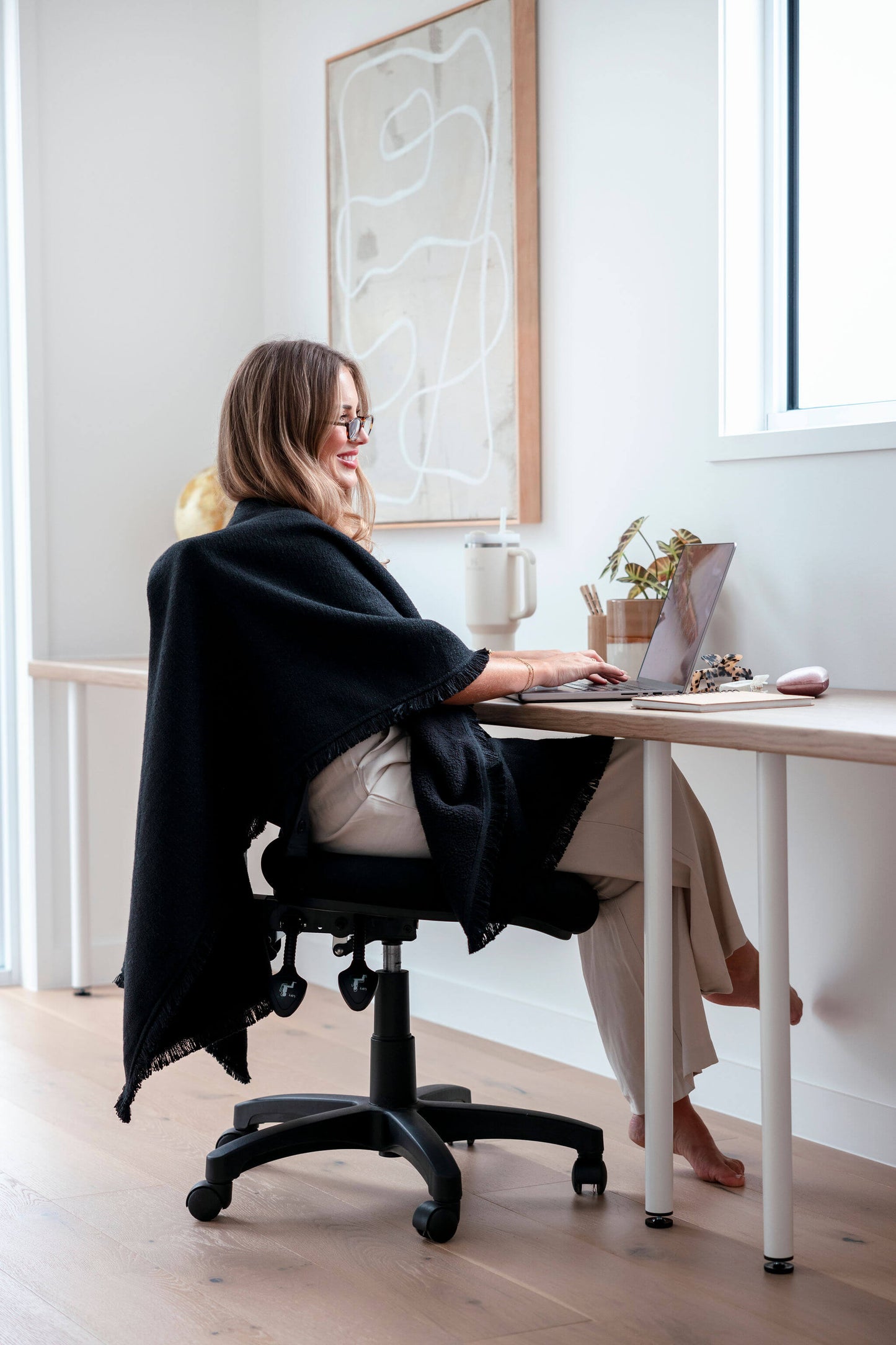 Professional woman in a modern office wearing the black Warmür office chair blanket, staying warm during meetings while maintaining a sleek and polished look.