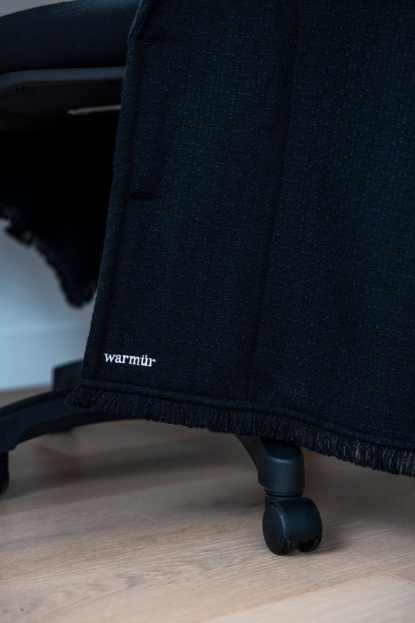 Luxurious black Warmür draped neatly over a desk chair, perfect for executives and professionals who want warmth without compromising style.