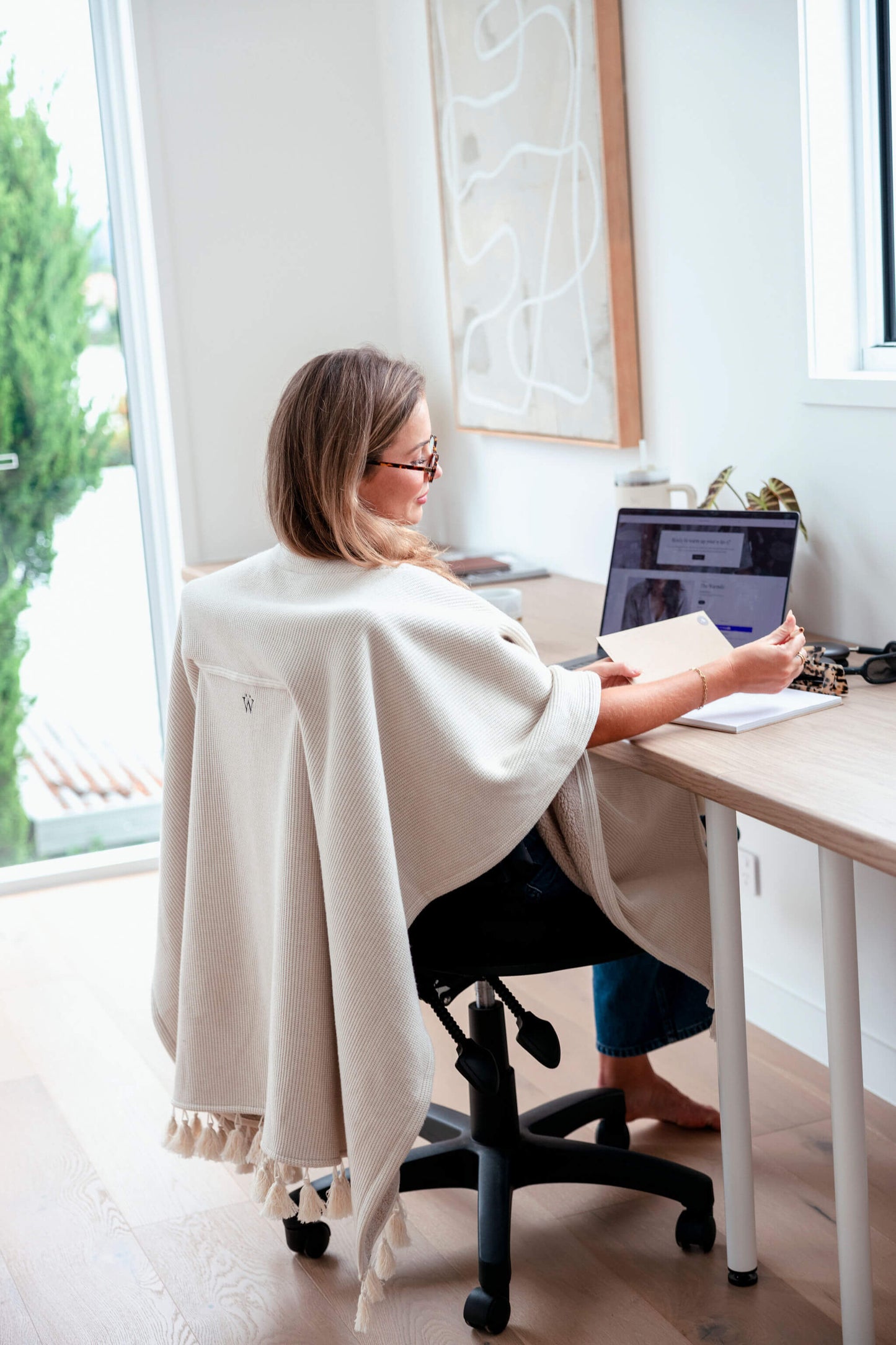 Professional woman staying warm at her desk with a beige office chair blanket that looks polished and modern.