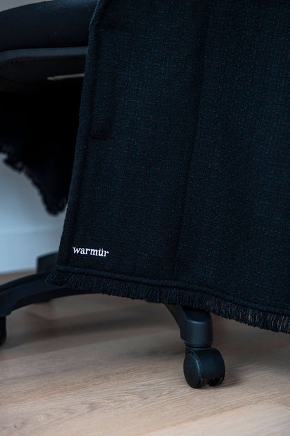 Luxurious black Warmür draped neatly over a desk chair, perfect for executives and professionals who want warmth without compromising style.